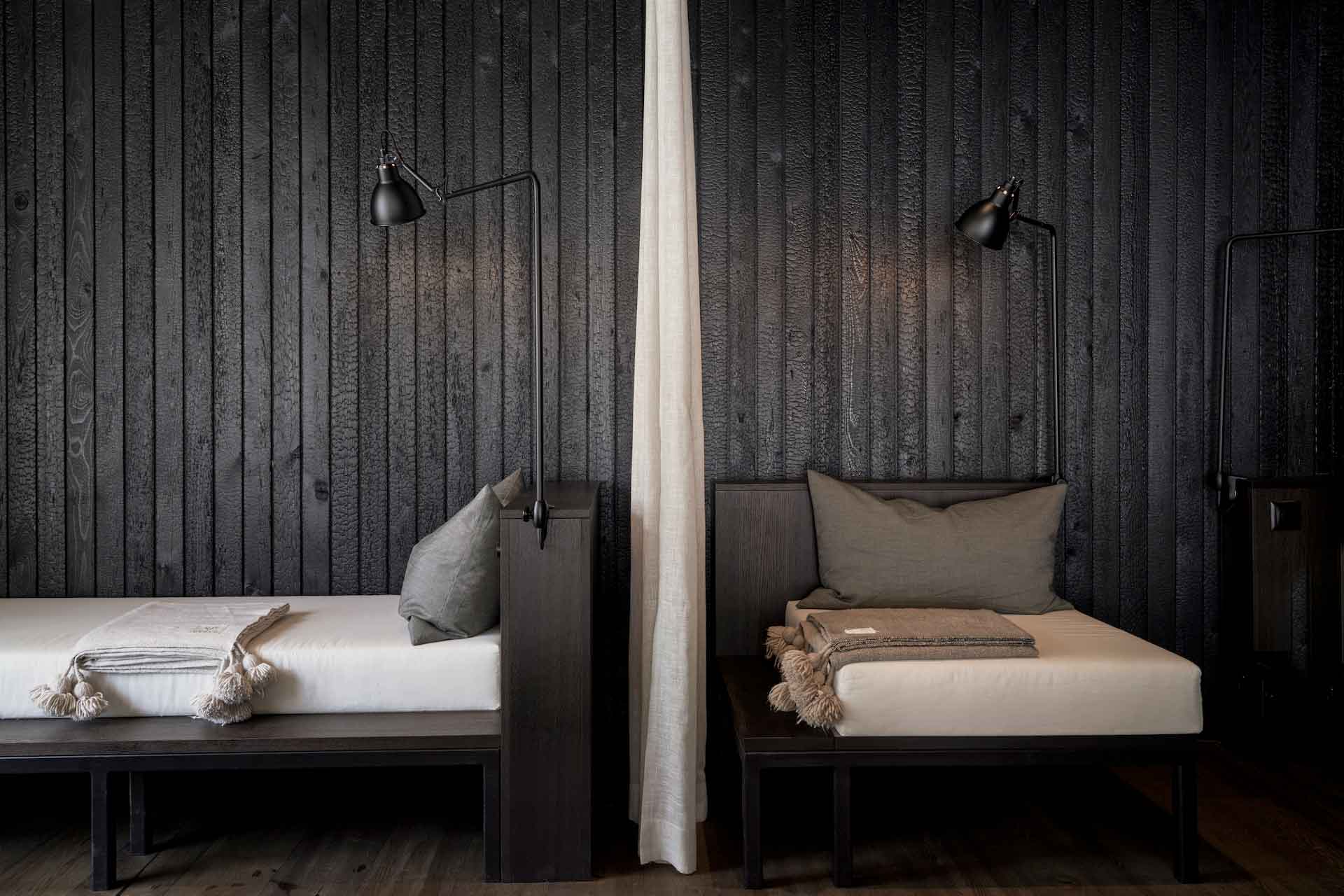 Zwei Liegen aus dunklem Holz im Spa des CERVO Mountain Resort Hotels in Zermatt, Schweiz