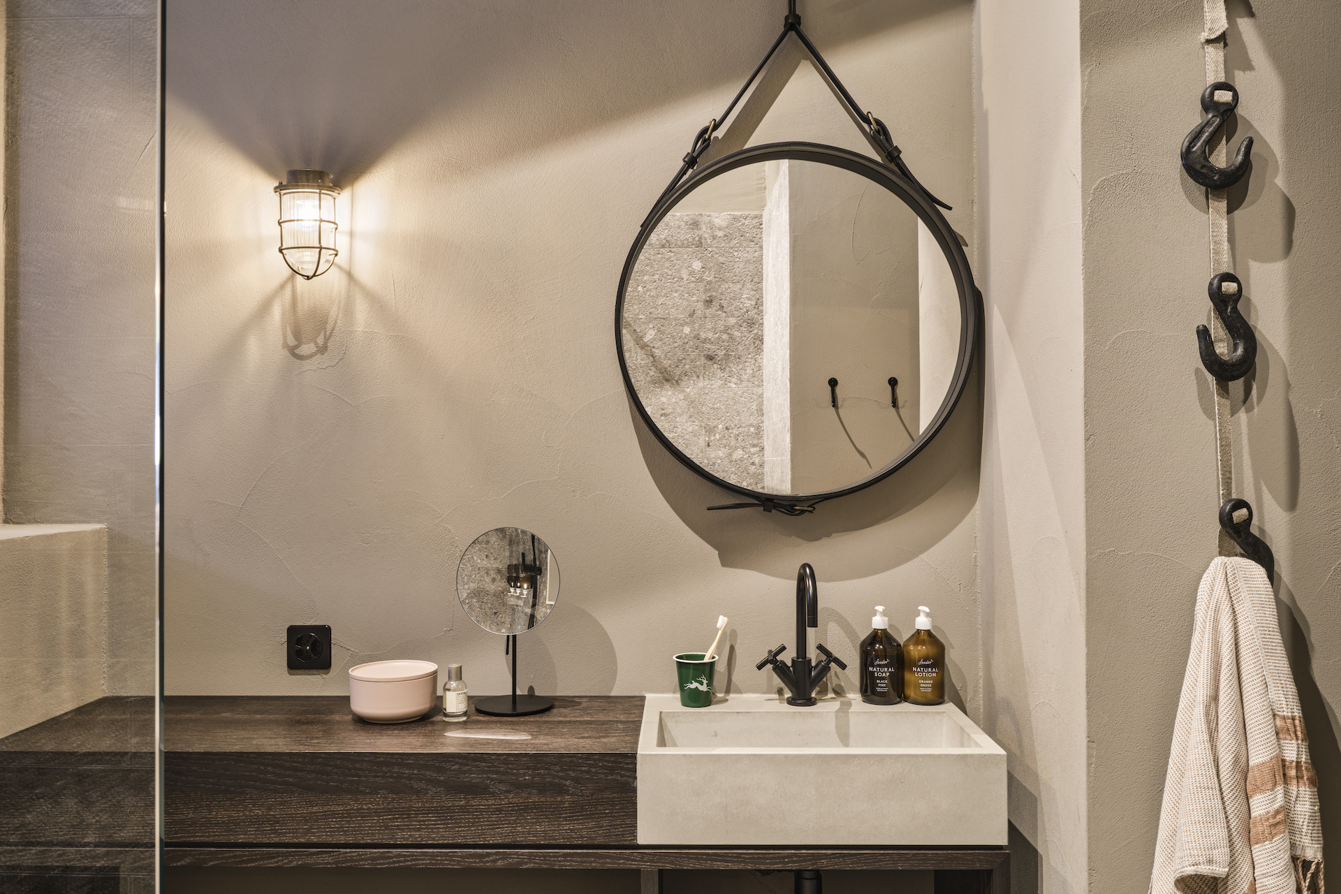 Badezimmer mit rundem Spiegel in einem Nomad Zimmer